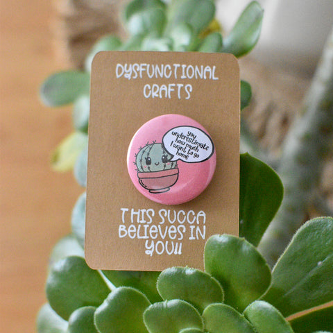 button badge- salmon pink background little Succa says "You underestimate how much I want to go home"